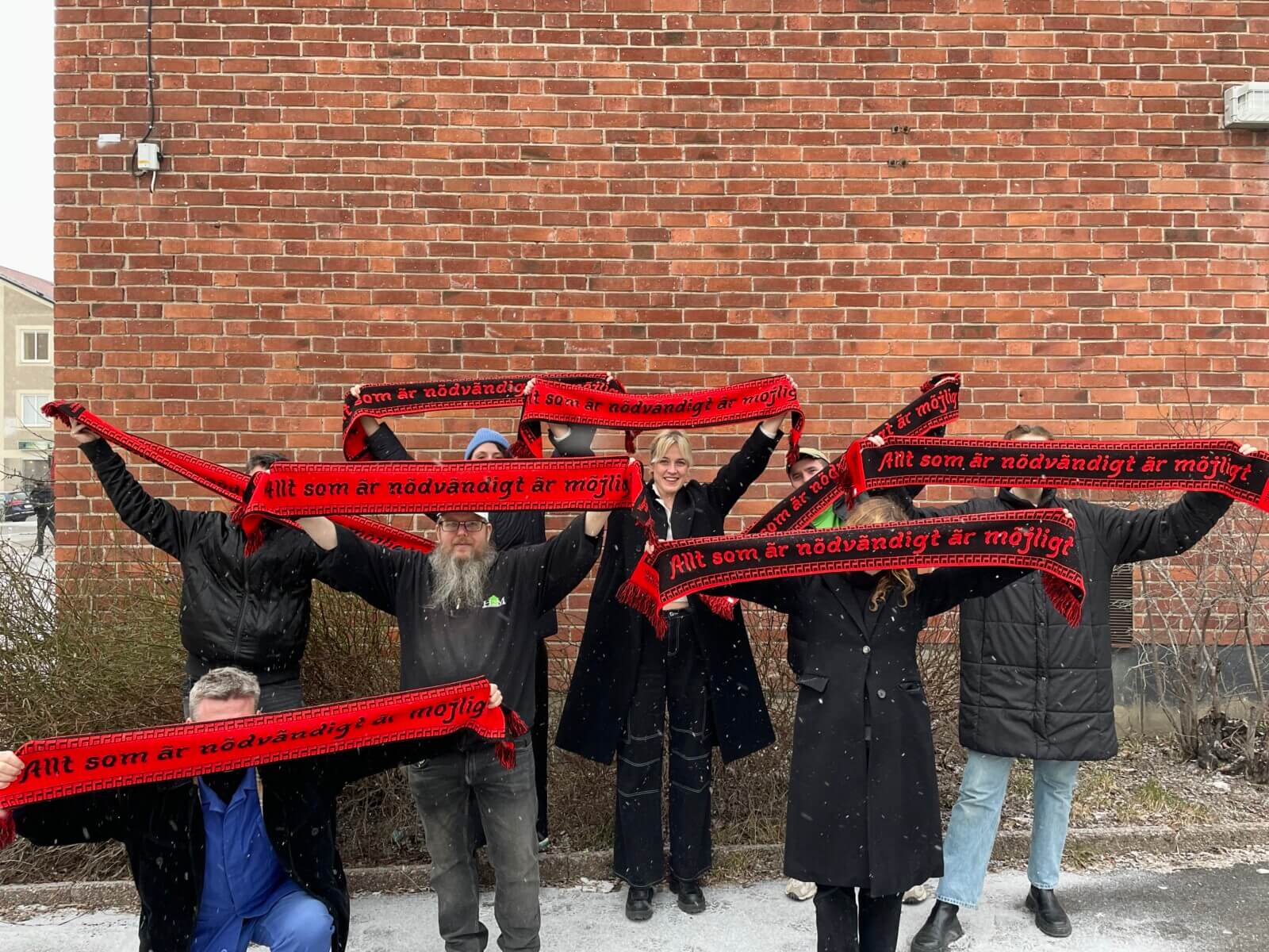 Fans av Hägerstensåsens Medborgarhus visar upp halsdukar med devisen "Allt som är nödvändigt är möjligt".